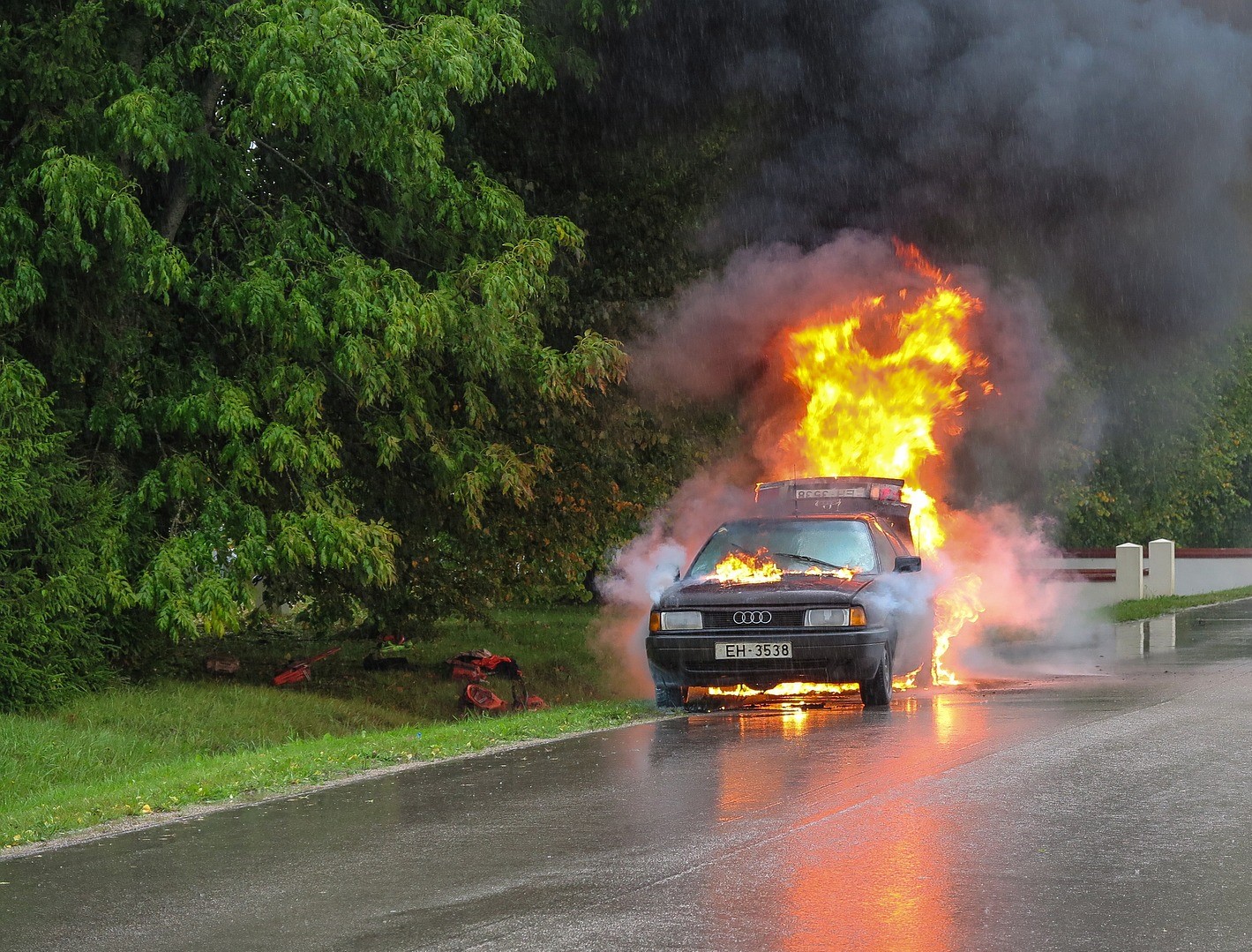 A car on fire in the middle of a road.